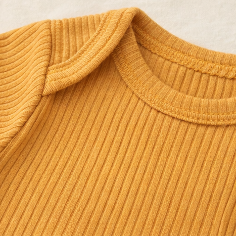 Collage of a mustard yellow ribbed baby onesie with buttons on a light background