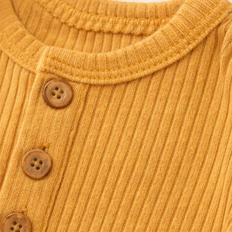 Close-up of a mustard yellow ribbed sweater with button details