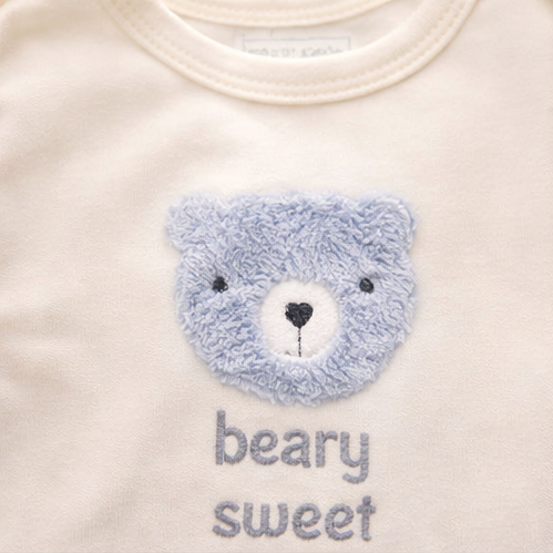 Collection of baby clothing items including a onesie with a bear face and 'bear sweet' text, striped shirt, and patterned fabric with animal designs.
