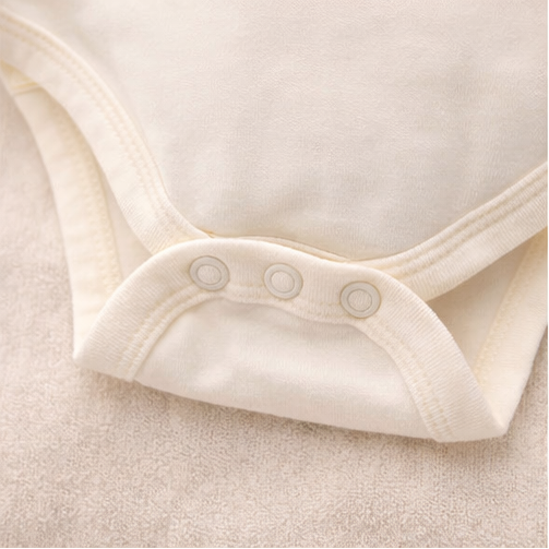 Collection of baby clothing items including a onesie with a bear face and 'bear sweet' text, striped shirt, and patterned fabric with animal designs.