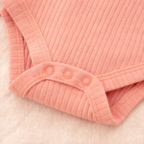Four baby rompers in pink, orange, peach, and yellow on a light background