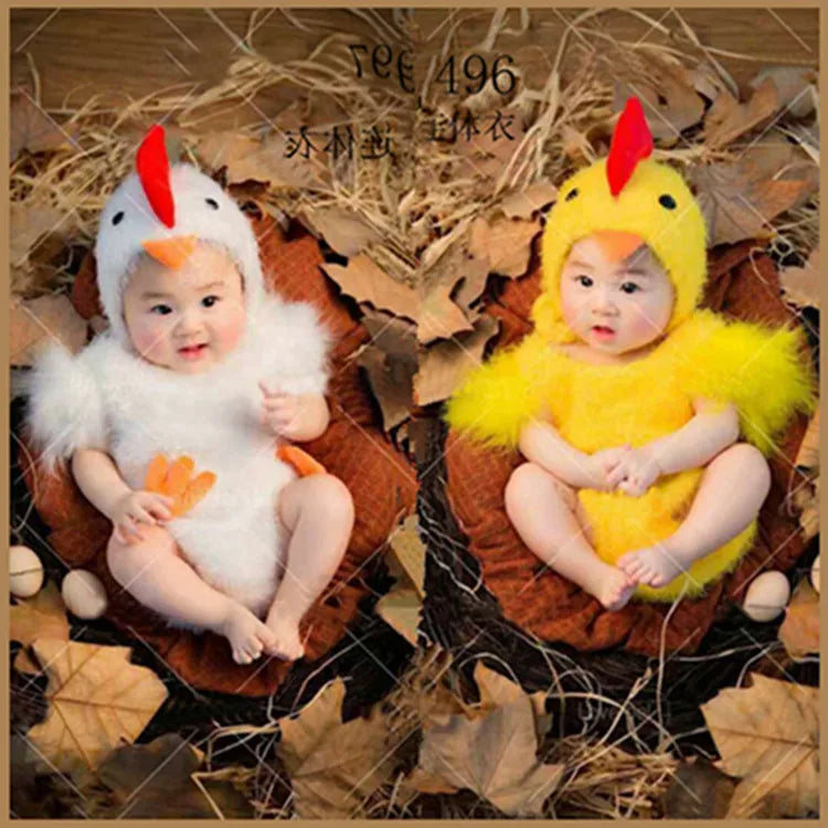 Two babies in yellow and white chicken jumpsuit costumes sitting in nests