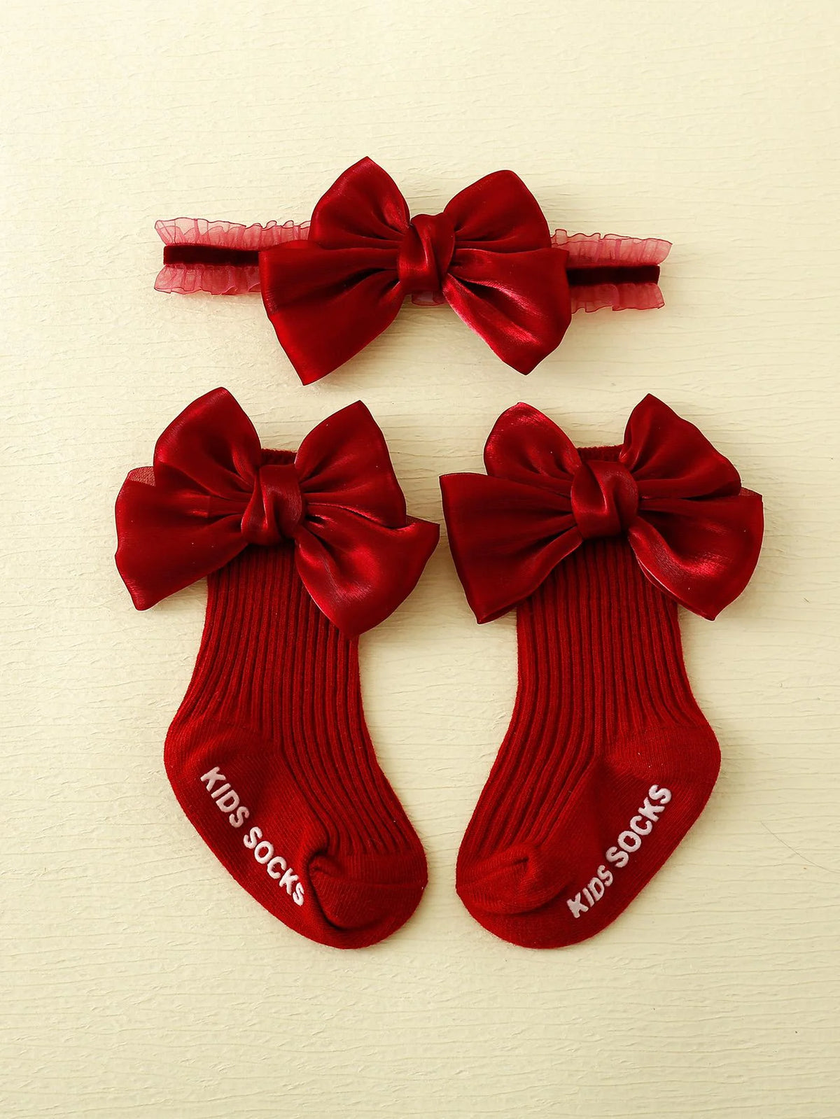 Red ribbed socks with large red bows and a coordinating bow headband with ruffled trim.