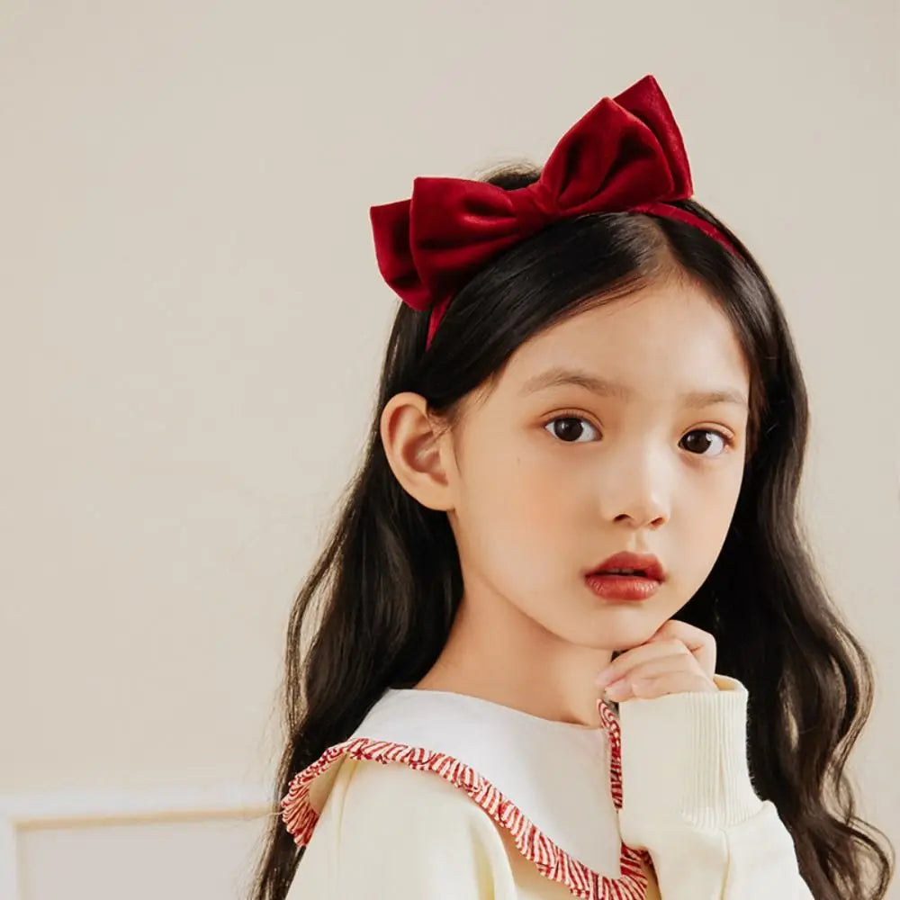 Red headband with a large side bow, shown worn in long hair.