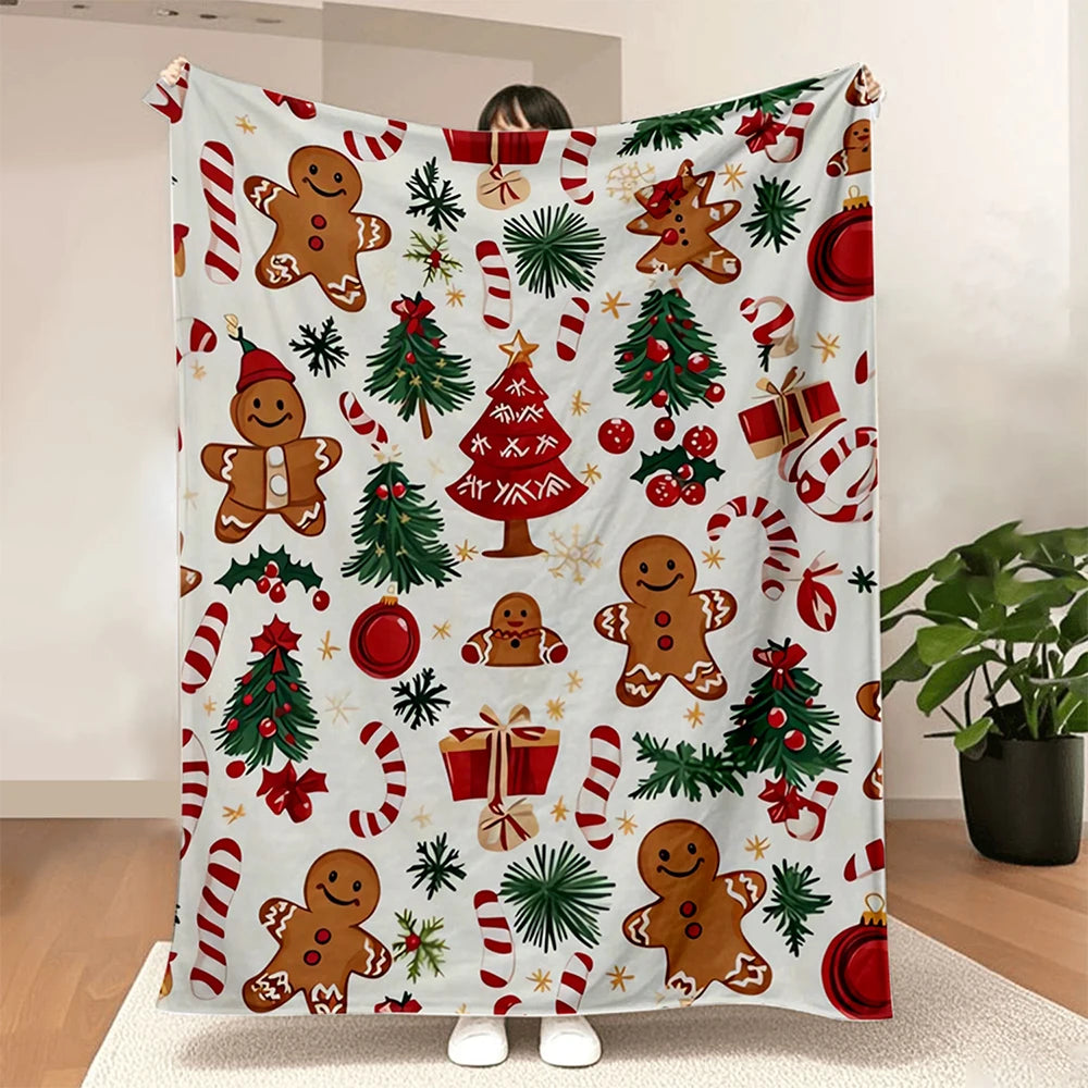 White throw blanket printed with gingerbread figures, red and green Christmas trees, candy canes, ornaments, and gifts.