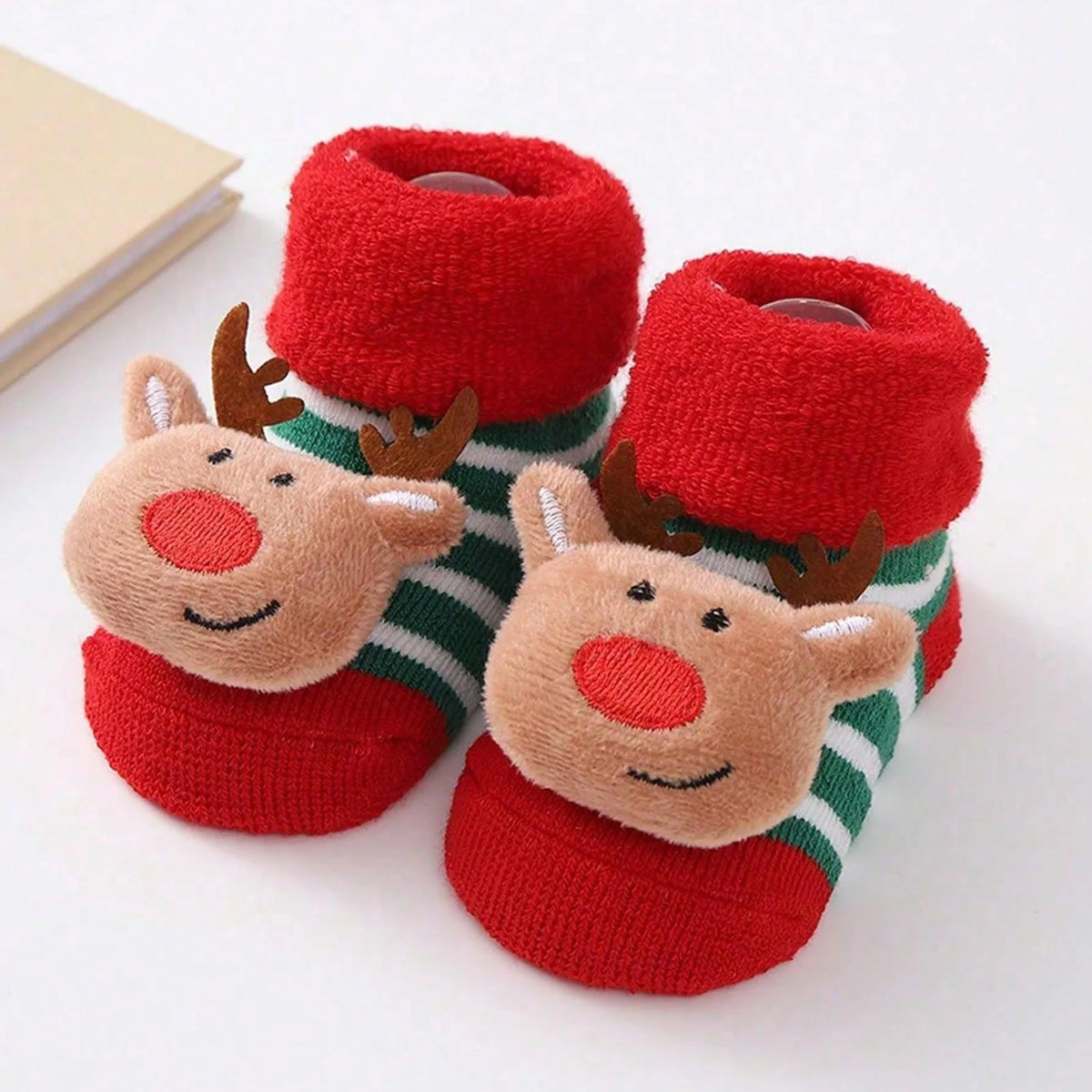 Green-and-white striped baby socks with red cuffs and toes and raised reindeer faces.