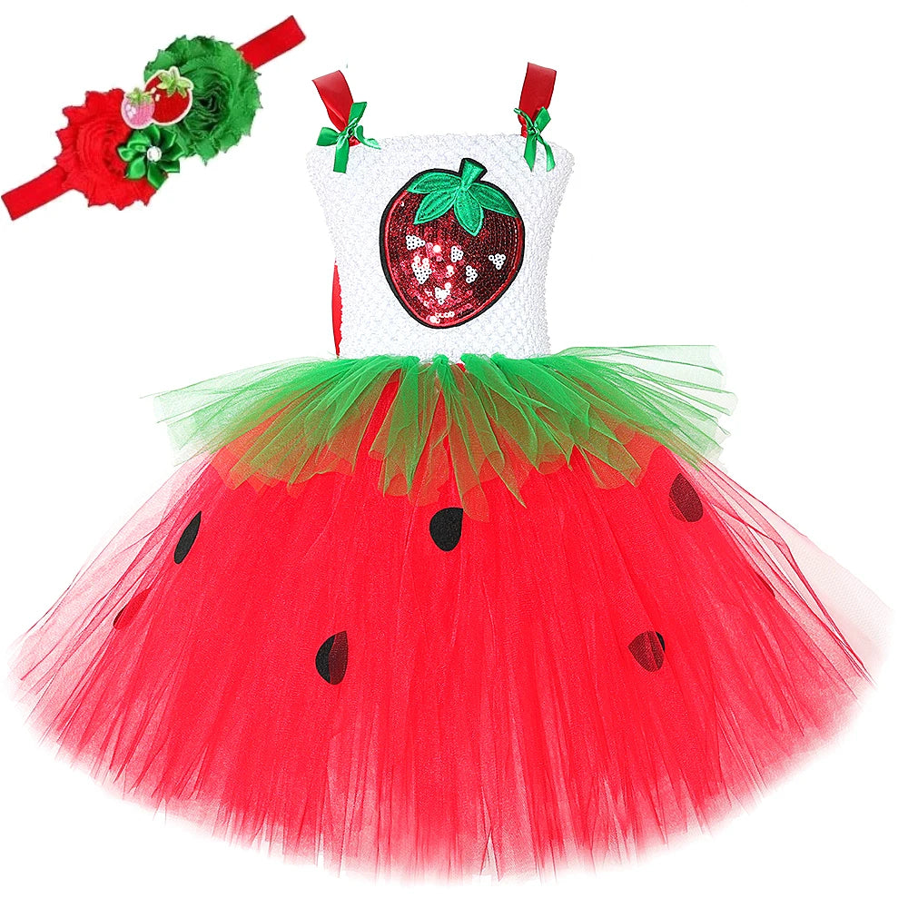 Close-up of white crochet top with red sequin strawberry applique and red straps with green bows on tutu dress