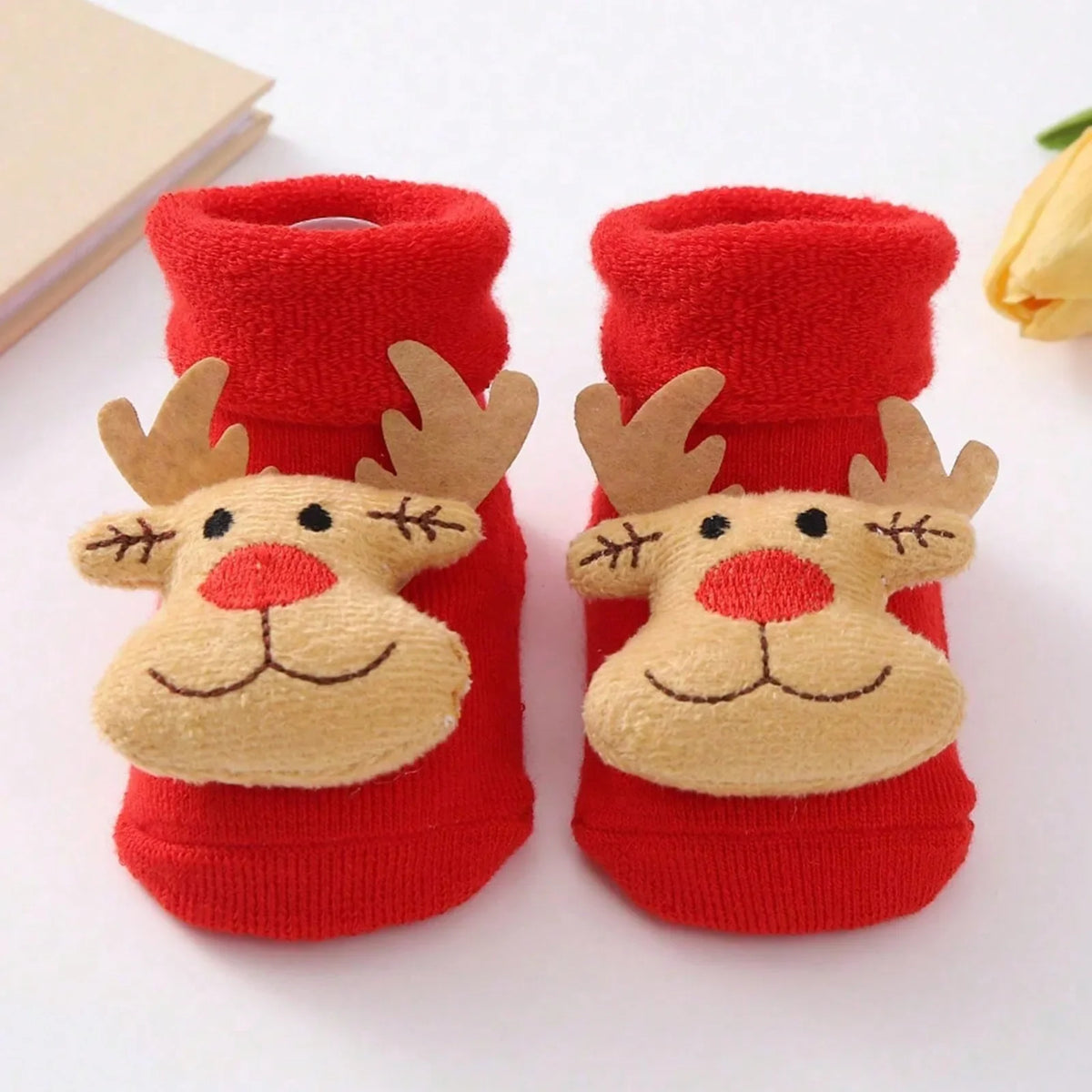 Red cuffed baby socks with tan reindeer face appliques, red noses, embroidered smiles, and light brown antlers.