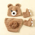 Brown hand-knit newborn bear costume with ear hat, pompom-tail shorts, and paw-print booties