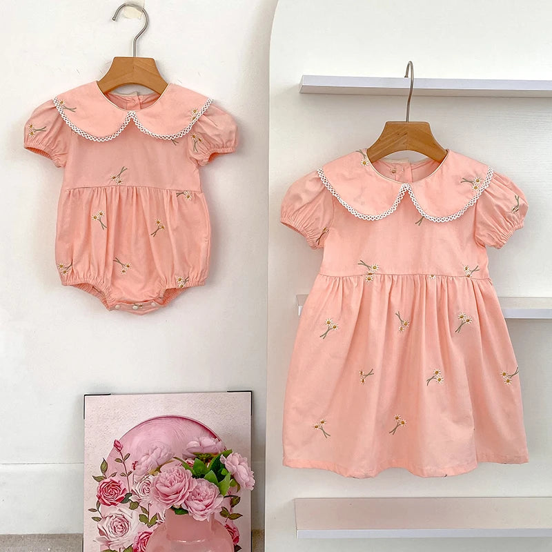 Close-up of embroidered floral details on girls romper and dress set