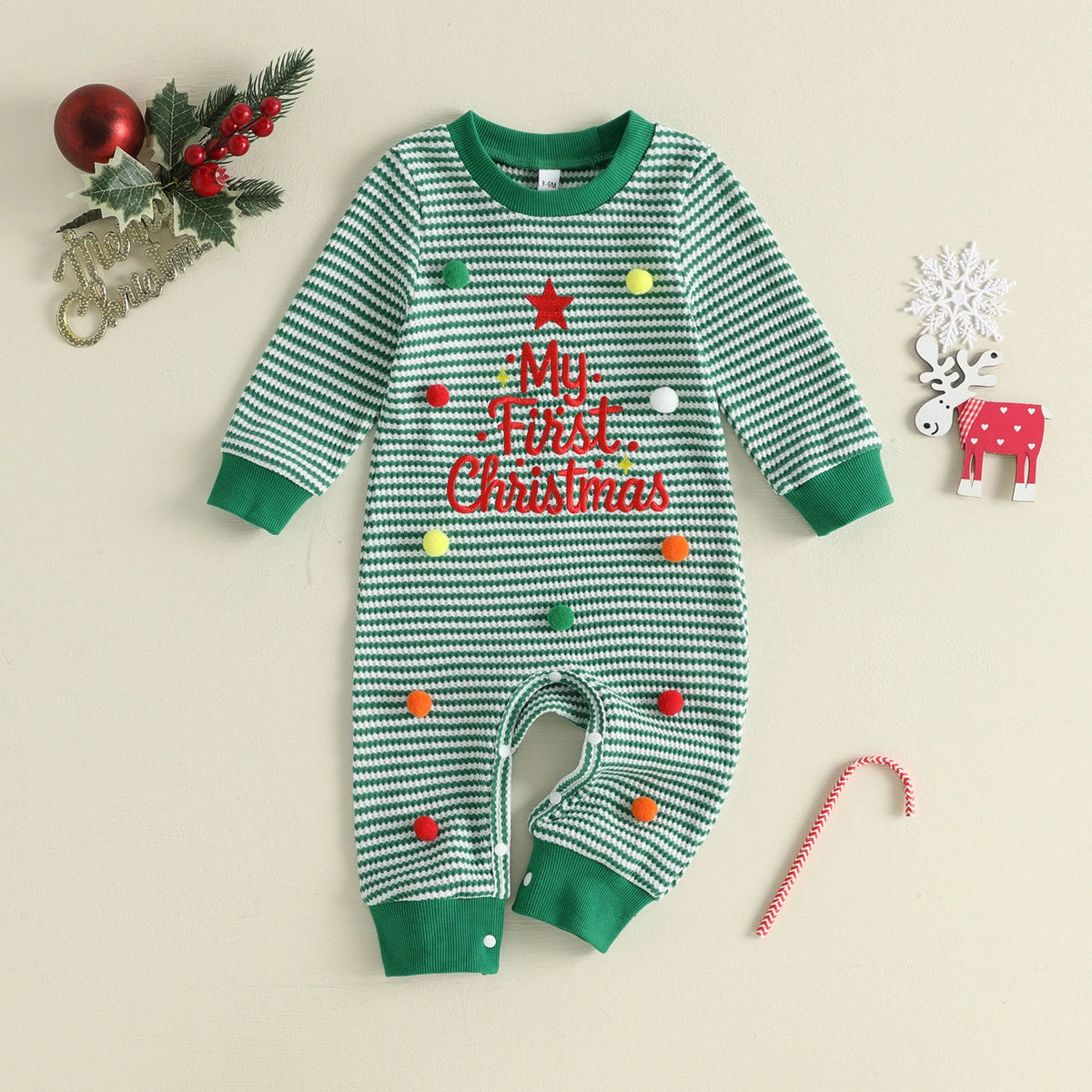 Green-and-white striped long-sleeve baby romper with red My First Christmas lettering, green cuffs, and colorful pom-pom details.