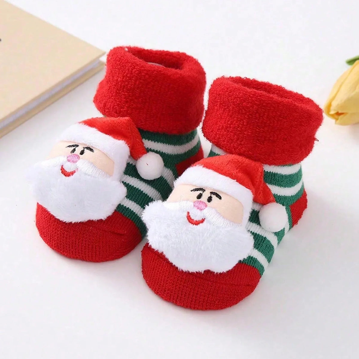 Green-and-white striped baby socks with red cuffs and toes and smiling Santa faces with white beards.