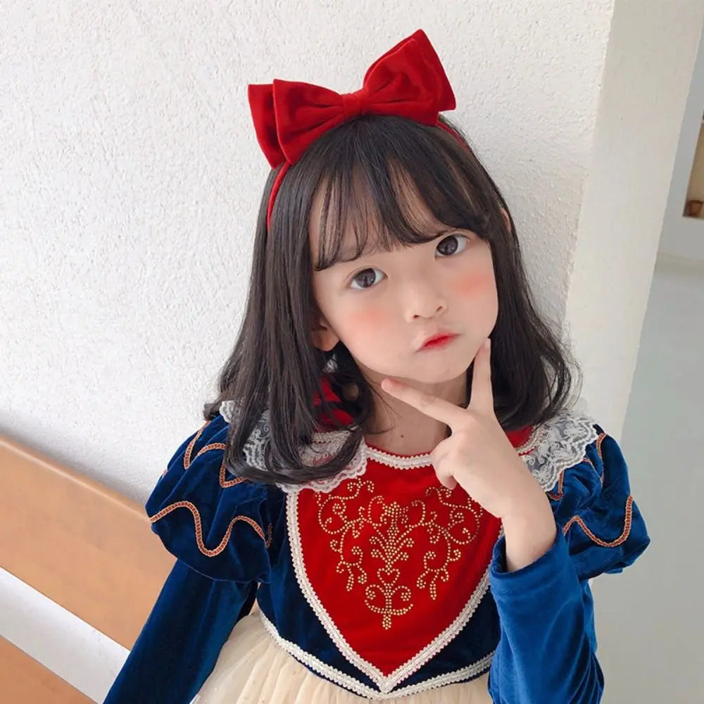 Child wearing a red headband with a large centered bow.