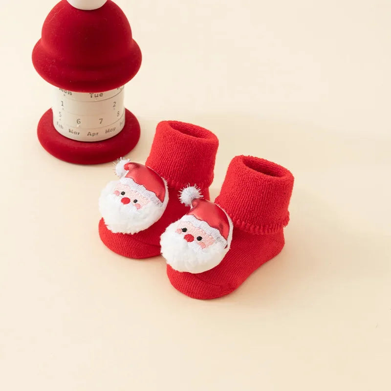 Red baby socks with folded cuffs and Santa face decorations with red hats and white beards.