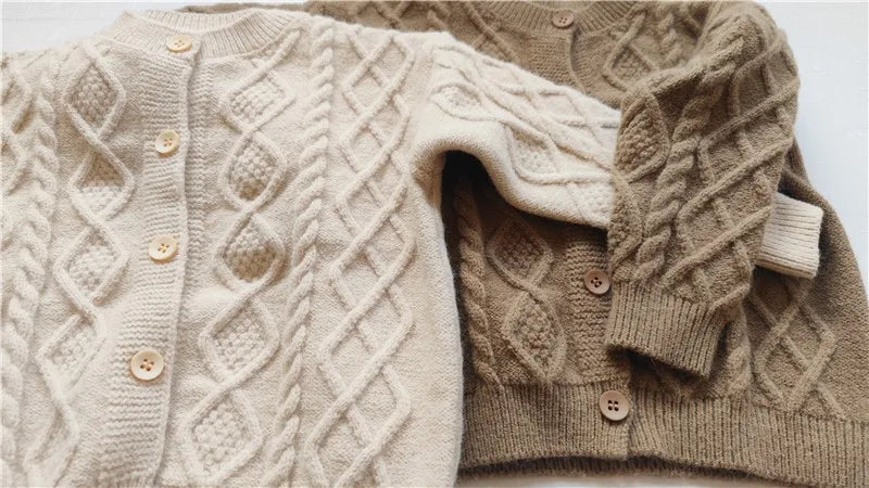 Baby wearing beige knit cardigan sweater outdoors
