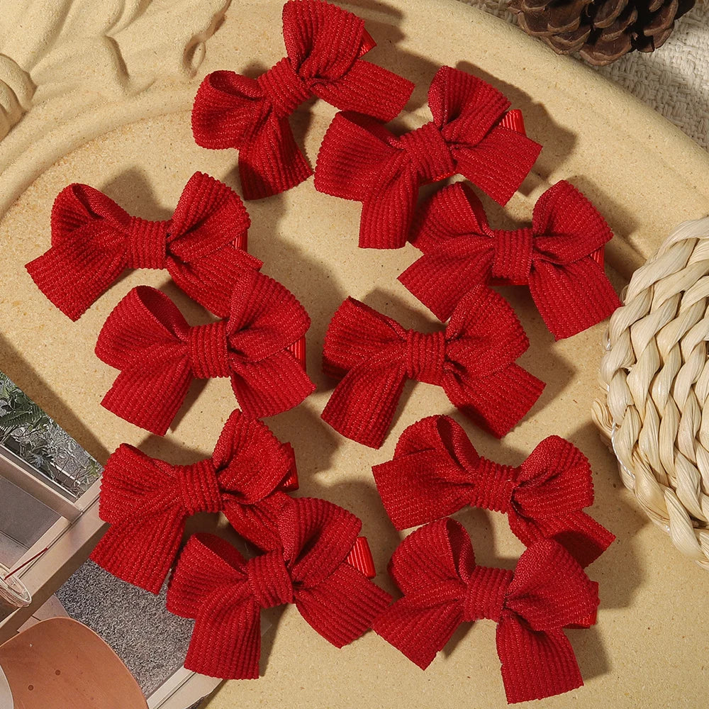 Ten red textured ribbon bow hair clips arranged on a beige surface.