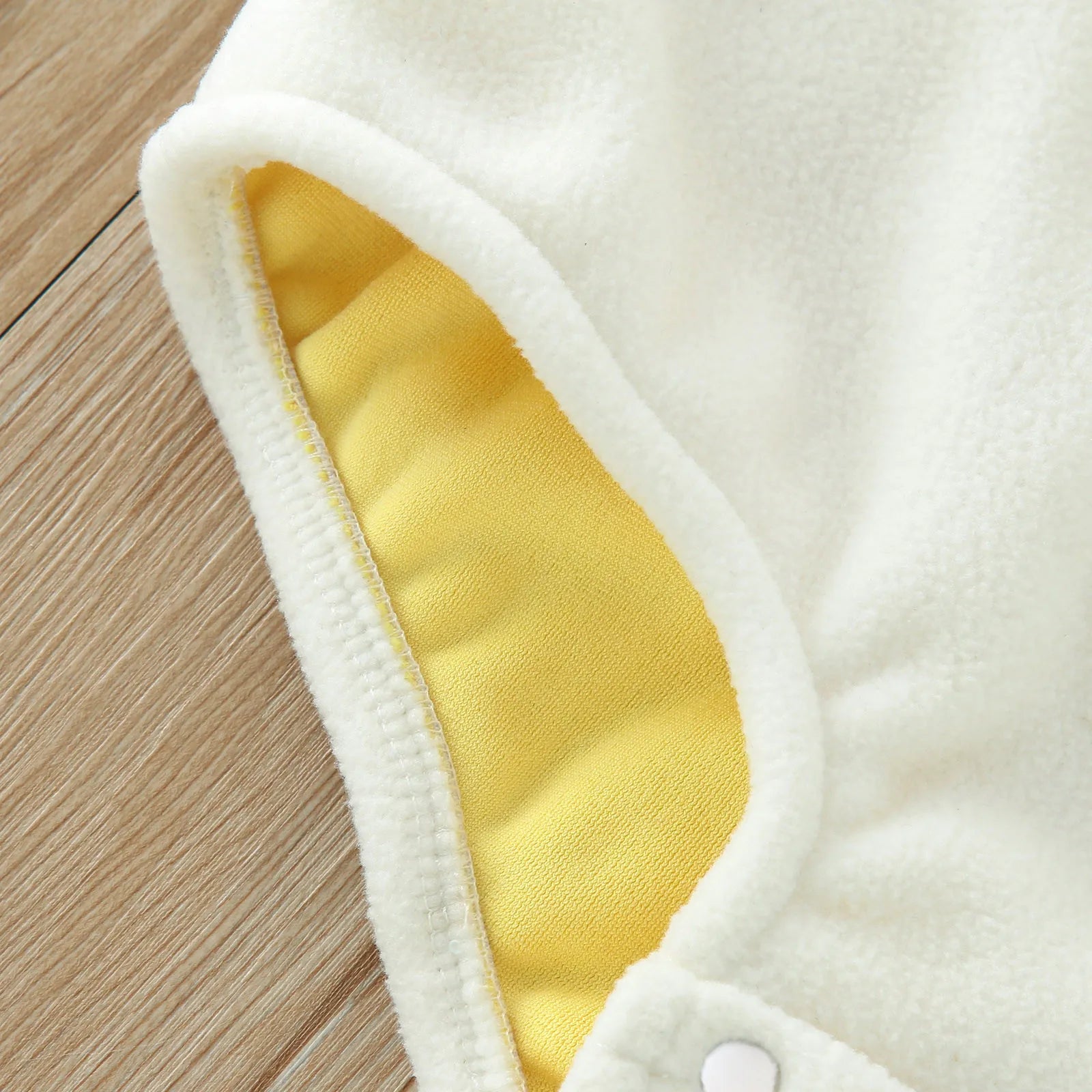 Close-up of white eggshell fabric detail on yellow chick costume romper