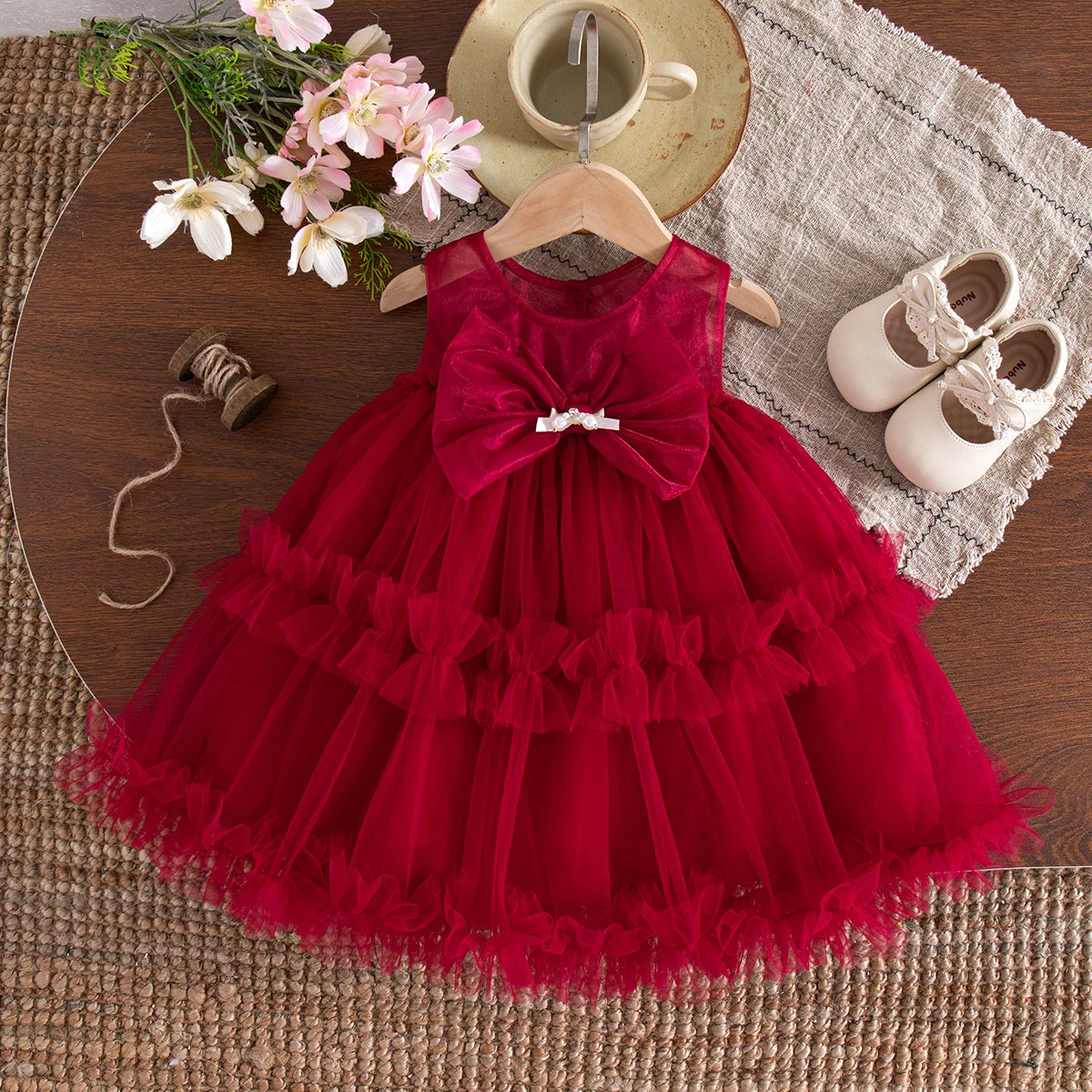 Red sleeveless dress with a large front bow and a layered sheer skirt with ruffled bands.