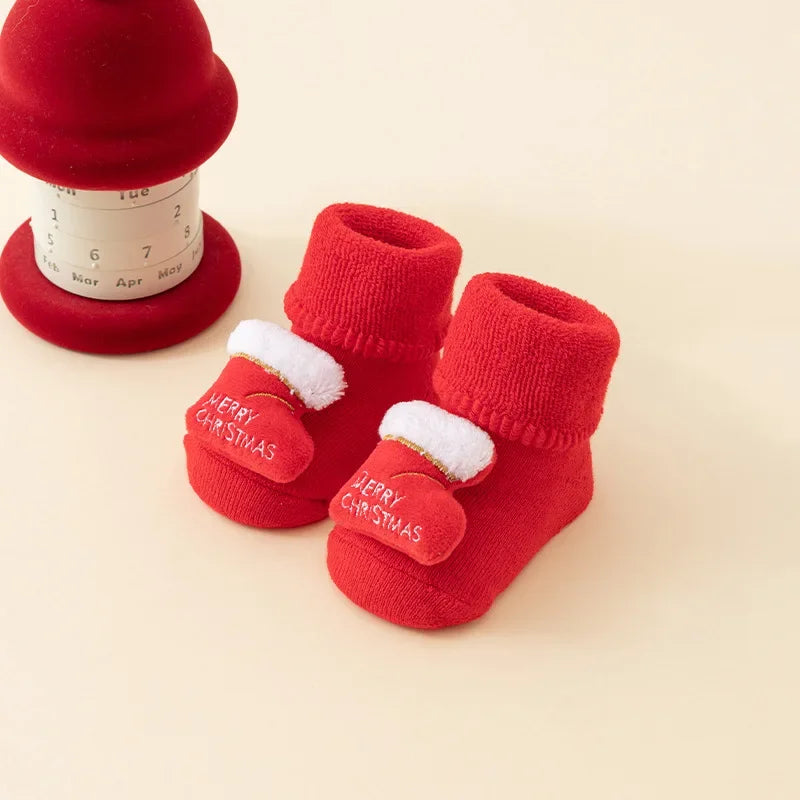 Red baby socks with folded cuffs and white-trimmed stocking decorations embroidered with Merry Christmas.