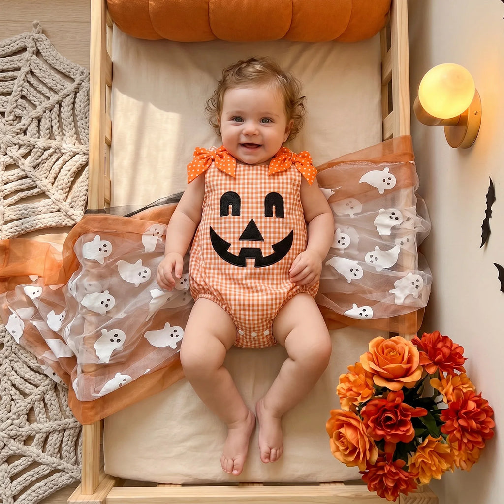 Baby wearing orange plaid jack-o'-lantern romper with Halloween decorations