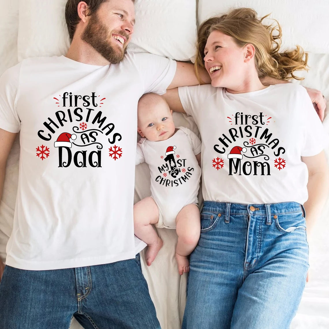 White first Christmas T-shirts for Mom and Dad beside a baby wearing a coordinating white bodysuit with red snowflake details.