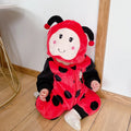 Child wearing red ladybug plush hooded romper costume sitting on floor