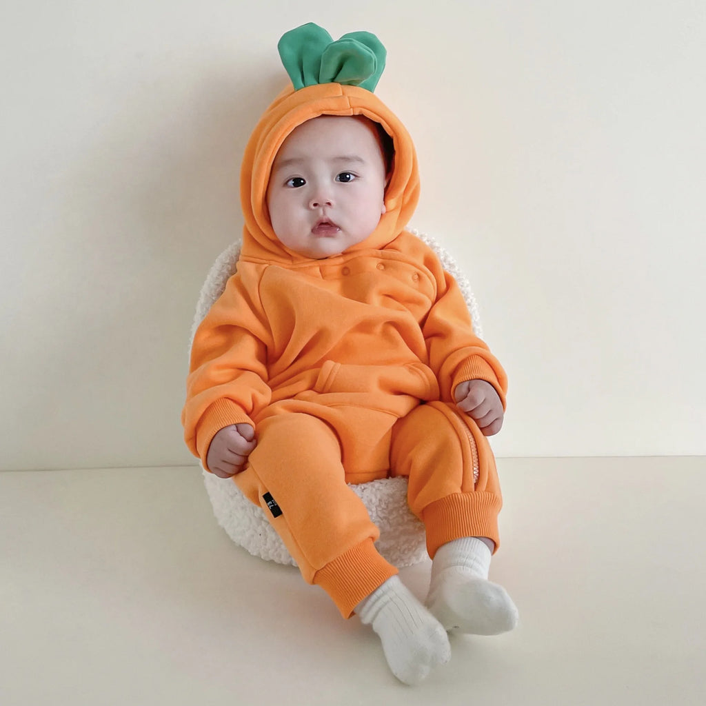 Baby wearing carrot costume jumpsuit sitting in chair