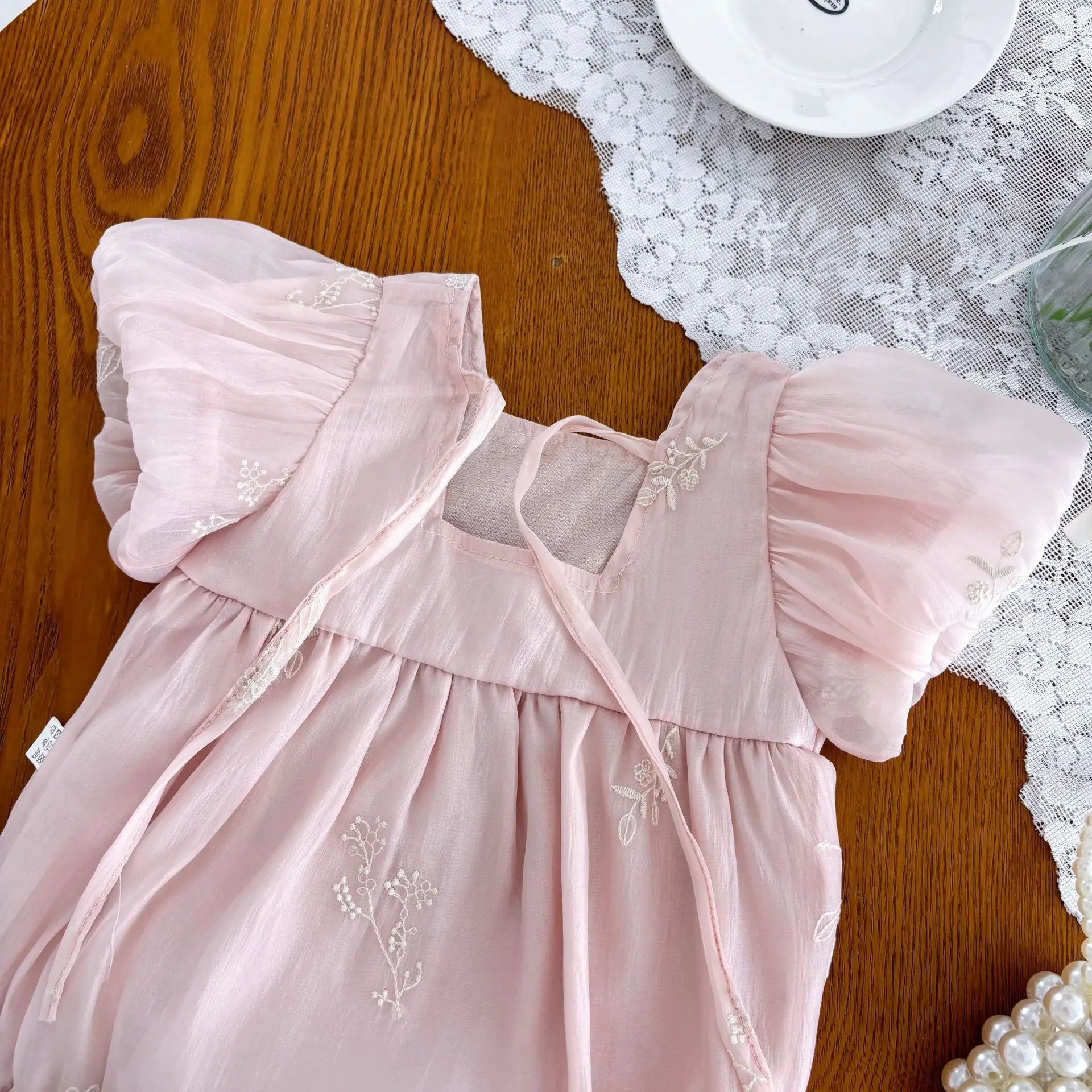 Back view of pink baby romper with embroidered details