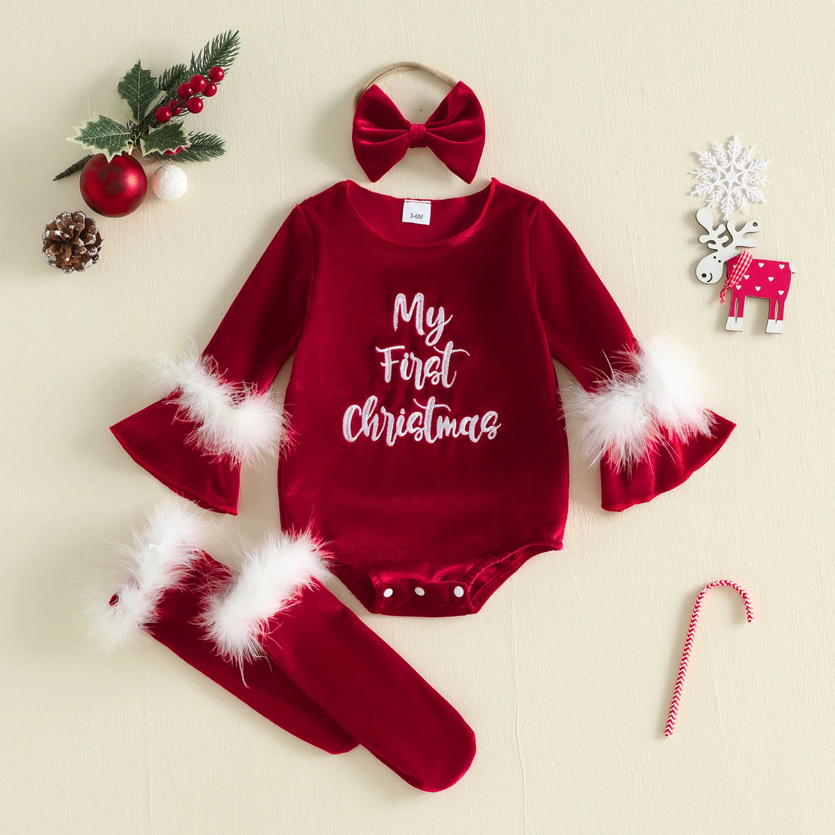 Red My First Christmas baby romper with flared sleeves and fluffy white trim, shown with matching stockings and a bow headband.