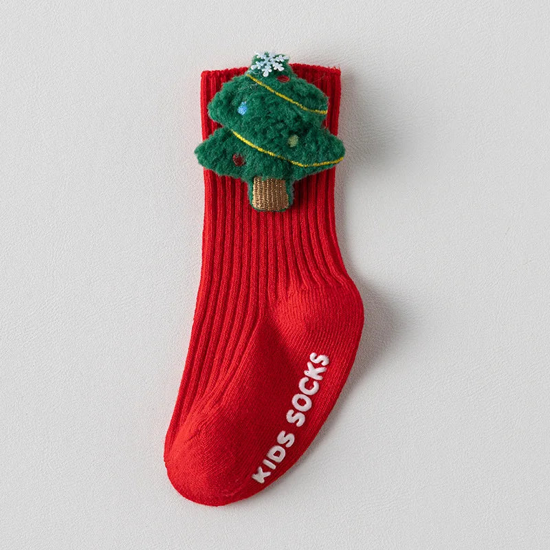 Red ribbed baby sock with a raised green Christmas tree, gold-colored garland, and white snowflake topper.