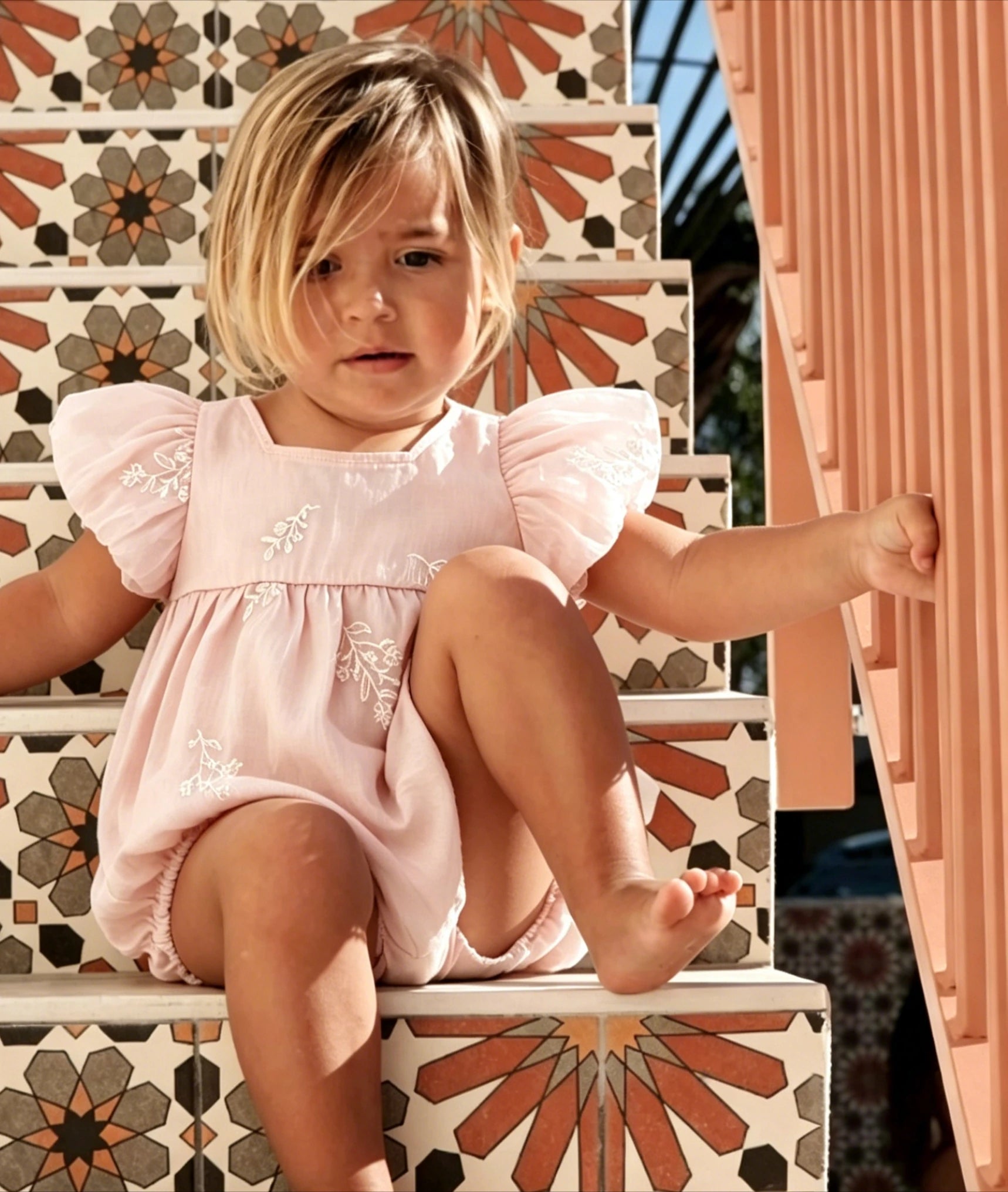 Front view of pink baby romper with embroidery and square collar