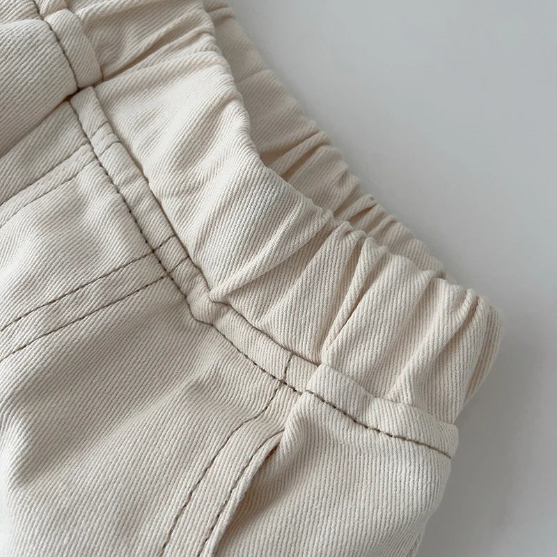 Elastic waistband, denim texture, and contrast stitching on beige pants