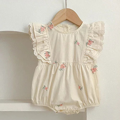 Flat lay of baby girl cotton bodysuit with floral embroidery