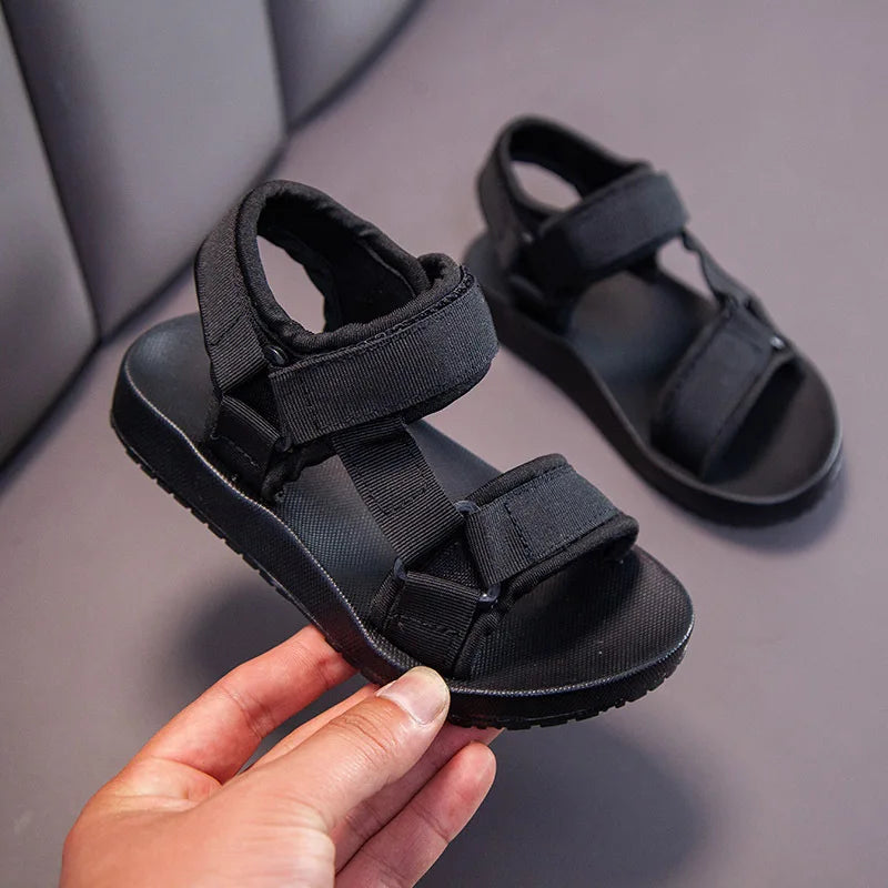 Black sport sandal held to show the two adjustable straps
