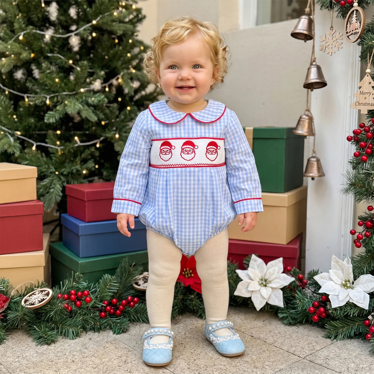 Child wearing a light blue gingham bubble romper with red piping, a rounded collar, and three embroidered Santa faces.