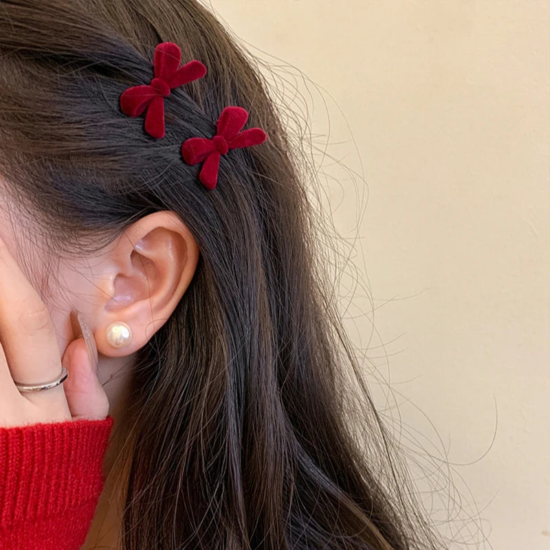 Two small dark red bow hair clips worn together above the ear.