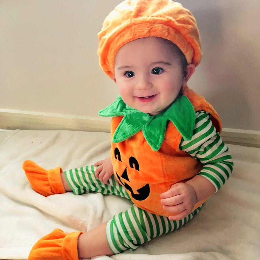 Baby wearing an orange pumpkin romper costume set with green leaf collar, matching pumpkin hat, and orange booties