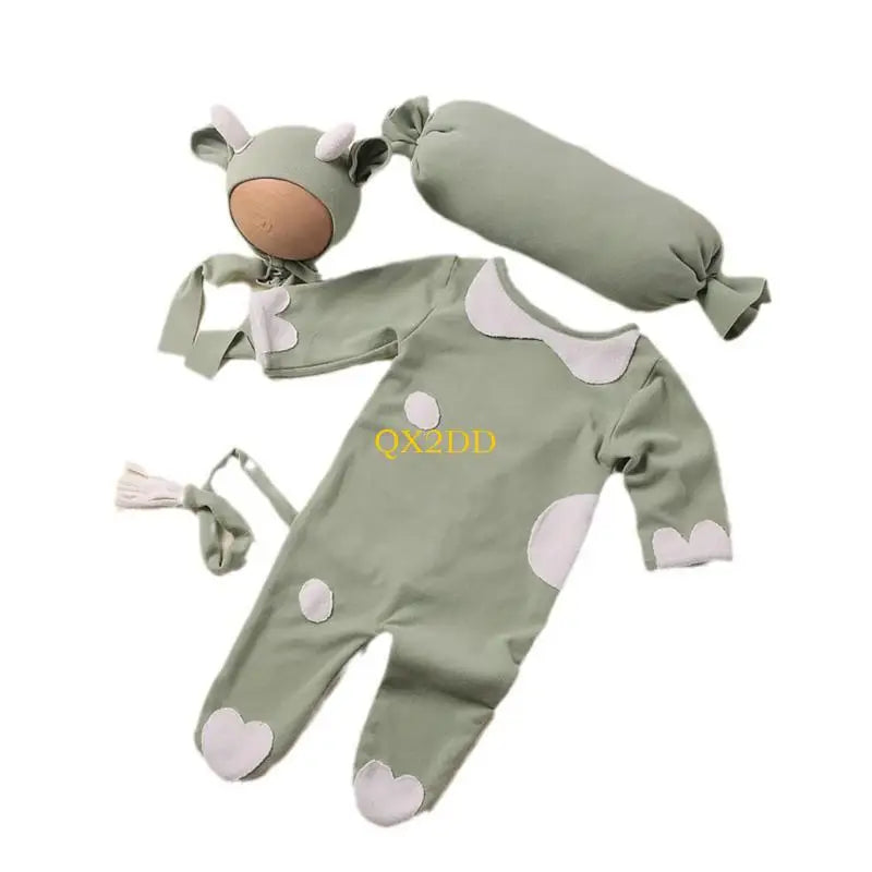 Green cow romper costume set laid out with hat and pillow