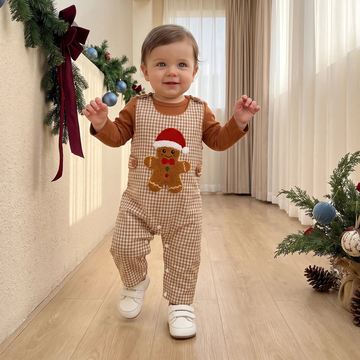 Child wearing beige gingham overalls with a gingerbread applique and a brown long-sleeve top.