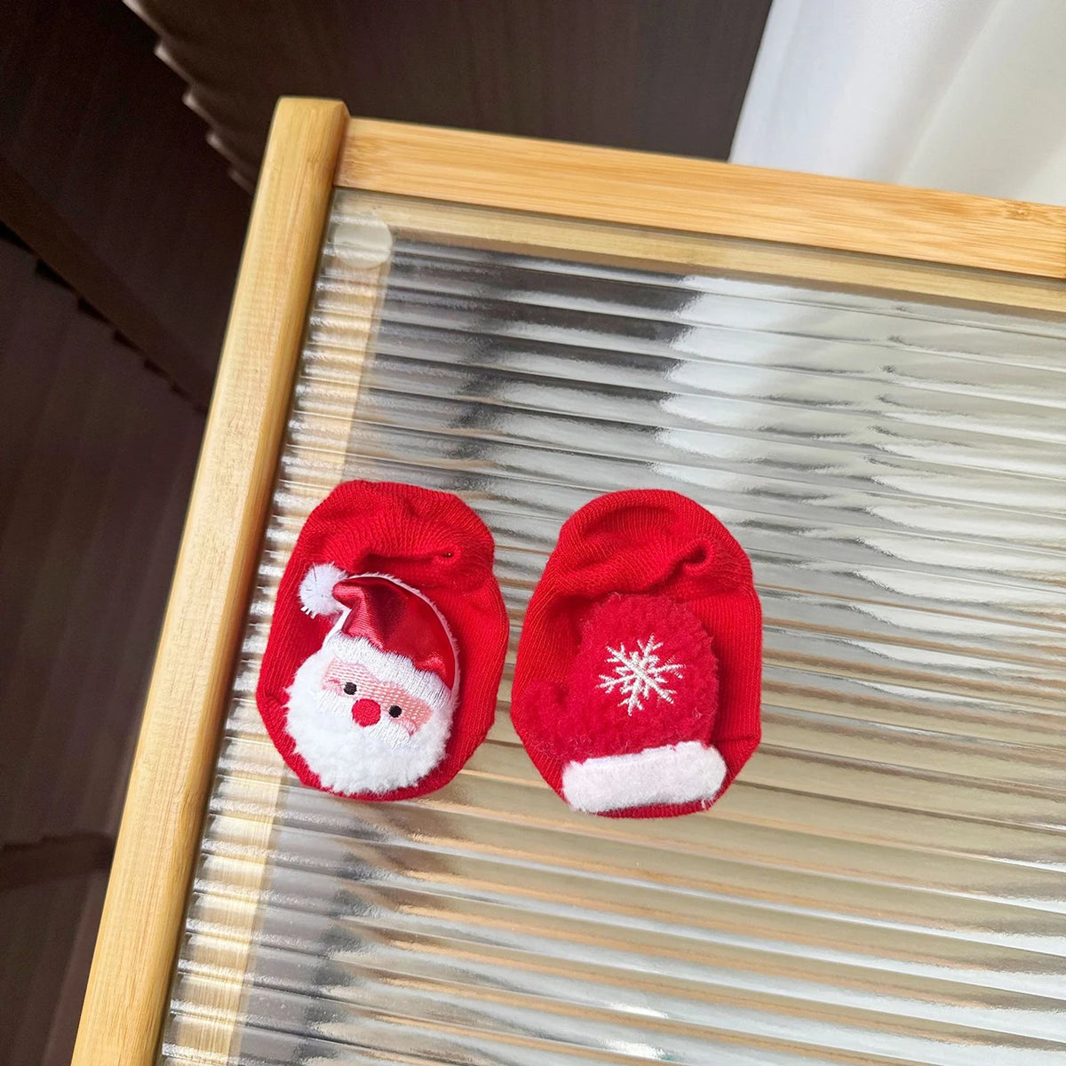 Red baby socks with a Santa face on one sock and a red mitten with a white snowflake on the other.