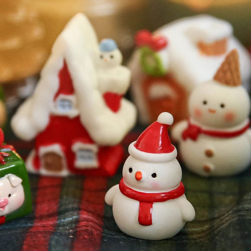 Mini resin snowman figurine in a red Santa hat and scarf, displayed in front of a Christmas scene.