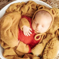 Newborn wearing red and mustard honey bear knit romper with matching ear bonnet