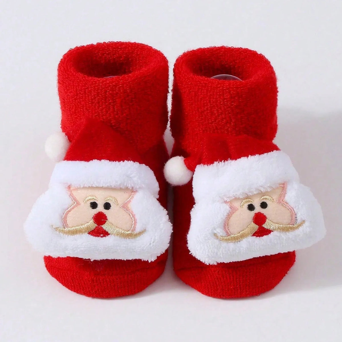 Red baby socks with folded cuffs and raised Santa faces outlined in gold-colored trim.
