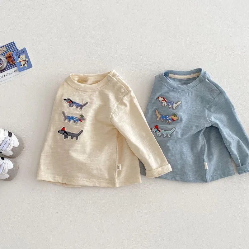 Beige and blue embroidered dog tops shown at an angle