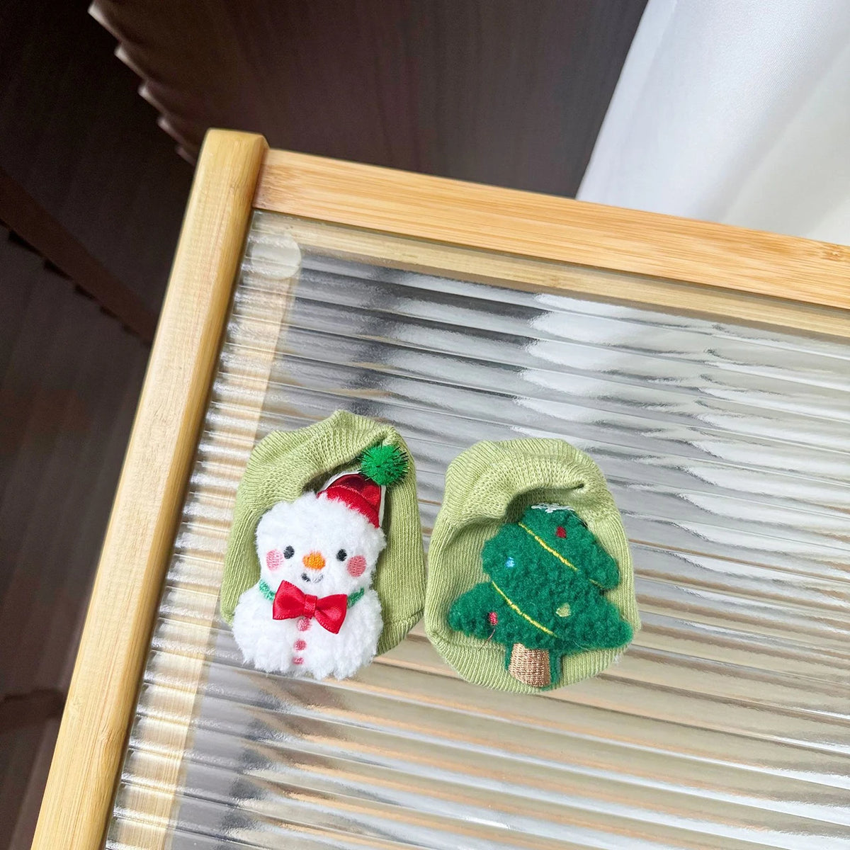 Light green baby socks with a textured snowman and a decorated Christmas tree.