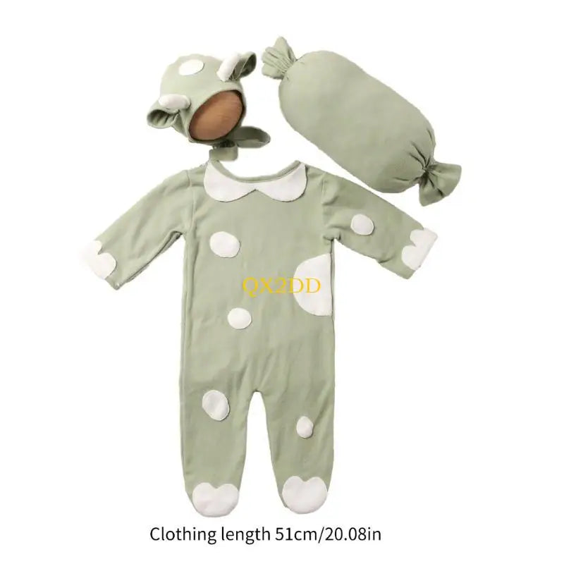 Green cow romper costume set laid out with hat and pillow