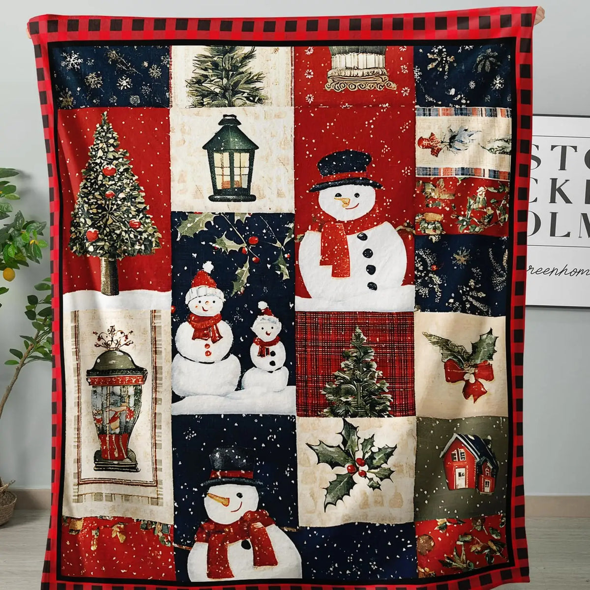 Christmas patchwork-print throw with snowmen, lanterns, trees, and holly, framed by a red-and-black checked border.