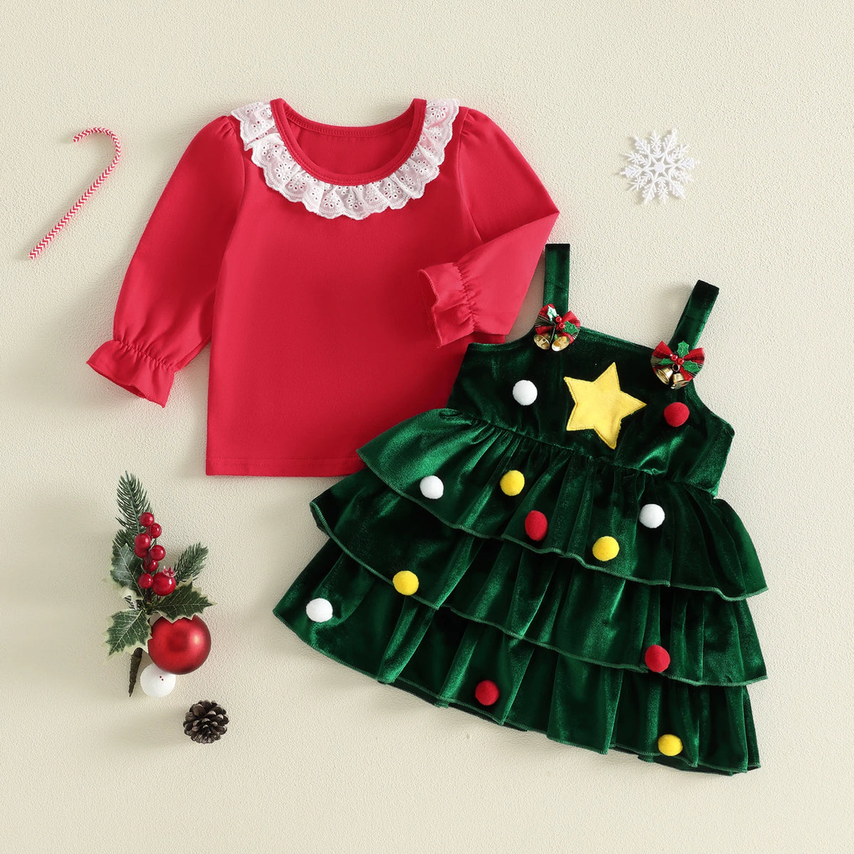 Green tiered Christmas tree pinafore with a yellow star and colored pom-poms, paired with a red long-sleeve top with a white ruffled collar.