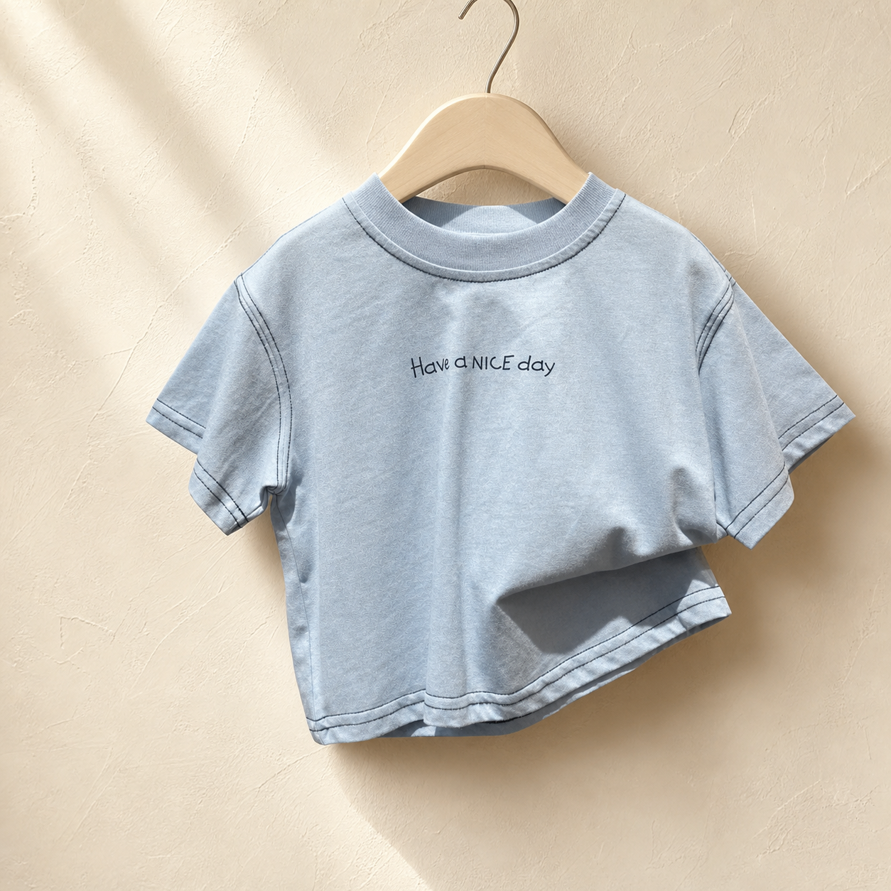 Close-up of Blue Have a Nice Day Short Sleeve Tee on a wood hanger