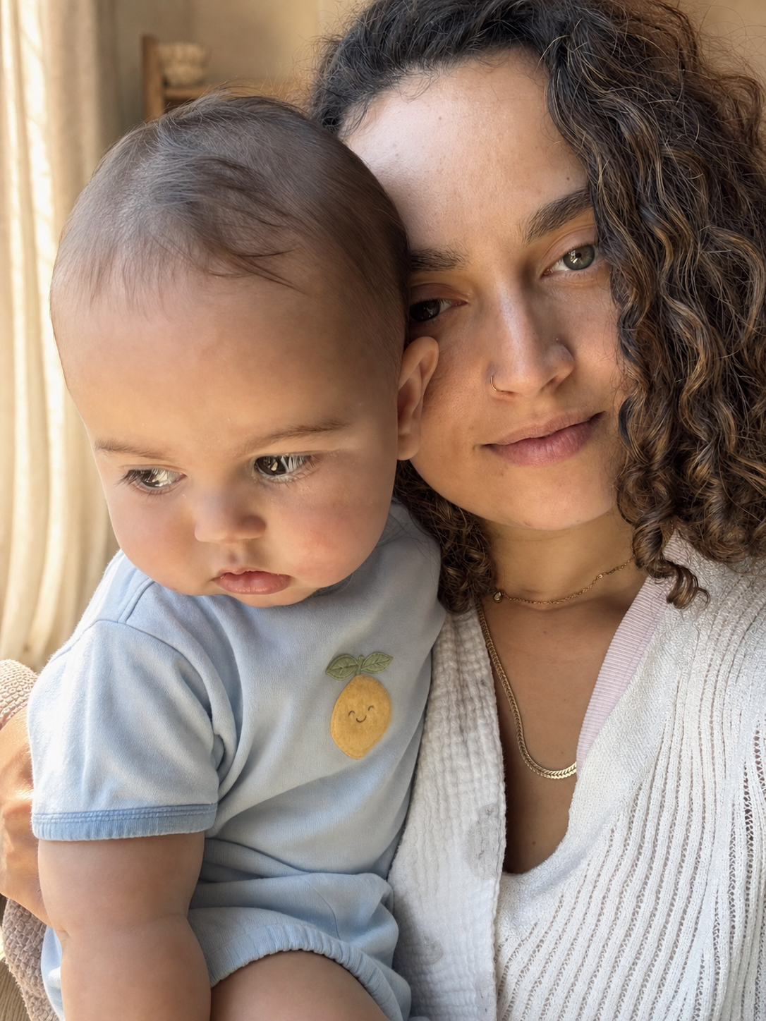 Orel, founder of GentleNest, holding her baby in a pale-blue fruit romper.